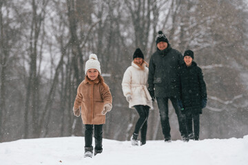 Fototapeta na wymiar Front view. Happy family is outdoors, enjoying snow time at winter together