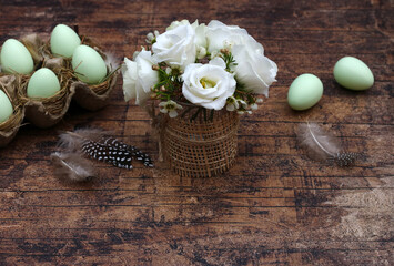 Blumenstrauß mit  grünen pastellfarbenen Ostereiern auf alten schäbigen Holz.