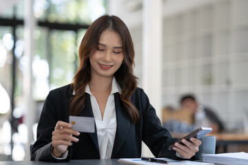 Obraz premium Asian businesswoman thinking and making a decision Shop online with a credit card in the office.