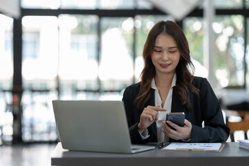 Attractive Asian businesswoman using a mobile phone at the office for making contact Talk about online business. and financial income happily.