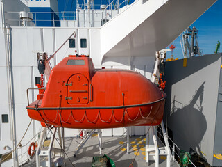 lifeboat on a cargo ship, for emergency evacuation. The boat is seen up close, with parts of the...