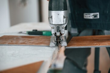 Cutting the planks. Man is installing new laminated wooden floor