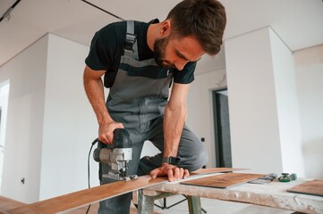 On the table. Cutting planks by the drill. Man is installing new laminated wooden floor