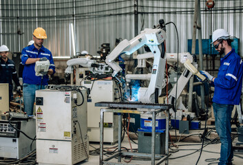 Two highly competent robotic operators collaborate to configure new automation using a computer-controlled panel display. The robot's coordination system for welding, cutting, and milling in a factory