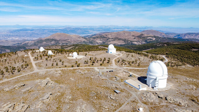 Drone aerial view of Calar Alto Observatory at the snowy mountain top in Almeria, Andalusia, Spain. Observatory domes skyshed.