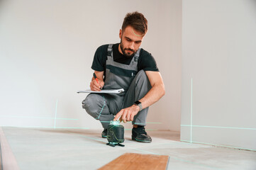 Laser leveler device. Man is installing new laminated wooden floor