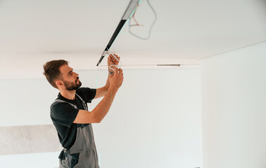 Installing lighting equipment on the ceiling. Man is working indoors at domestic room
