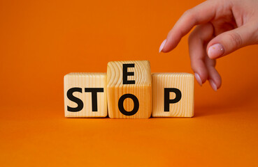 Step vs Stop symbol. Businessman hand points at turned wooden cubes with words Stop vs Step. Beautiful orange background. Step vs Stop and business concept. Copy space