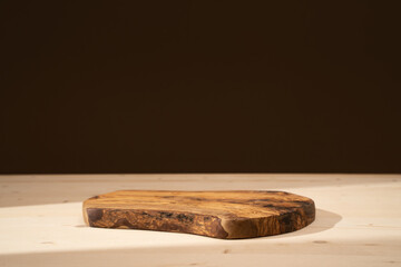 Olive wood board podium for cosmetic products, perfumes or food against brown background. Front...