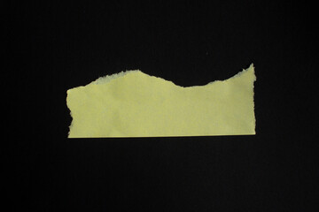 Ripped blank yellow paper on a black background. Paper edge with copy space.
