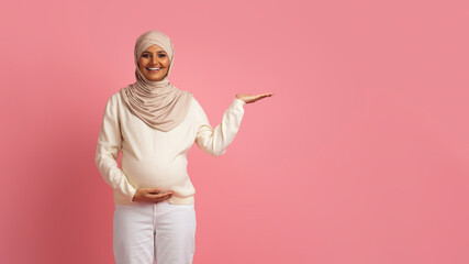 Nice Offer. Smiling Pregnant Muslim Woman Demonstrating Something At Her Empty Palm