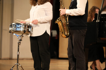 The band performing at the concert playing musical instruments on the drum saxophone and piano