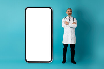 Handsome european doctor pointing at huge phone with white screen