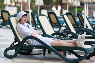 The nurse is resting chair while on duty near the pool.