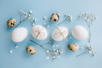 Composition with Easter eggs and flower blossom on blue background. Minimal easter concept.