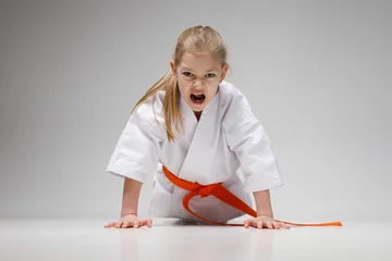 Tischdecke Angry baby girl in a kimono is doing push-ups on a white background, karate training. © Andrii Zastrozhnov