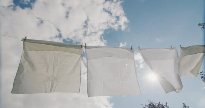 Bed linen hanging on a clothesline and drying against a blue sky
