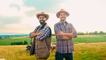 Happy Caucasian handsome men farmers posing to camera, crossing hands and smiling in field....