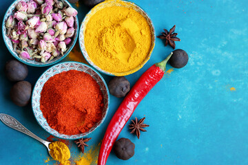 Colorful still life with three ceramic bowls full of spices. Turmeric, paprika powder, dried roses, anise close up photo. Indian culture concept. 