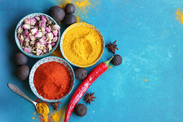Colorful still life with three ceramic bowls full of spices. Turmeric, paprika powder, dried roses,...
