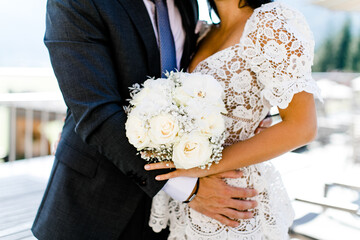Brautpaar mit Anzug und weißem Blütenkleid und weißem Brautstrauss