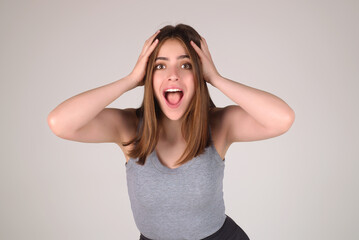 Surprised shocked young girl isolated over gray studio background. Close up shot of emotive shocked young woman opens mouth widely, Wow, unbelievable. People expressive emotions.