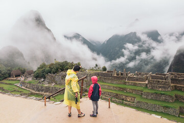 Peruvian mother showing her daughter the ruins of Machu Picchu - obrazy, fototapety, plakaty