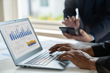 A group of Asian businessmen are brainstorming to analyze financial reporting situations. Calculate investments with income, tax and accounting calculators from graphs data on laptop at desk.