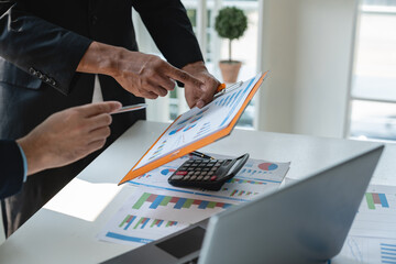 A group of Asian business people are brainstorming and clarifying to analyze the financial report...