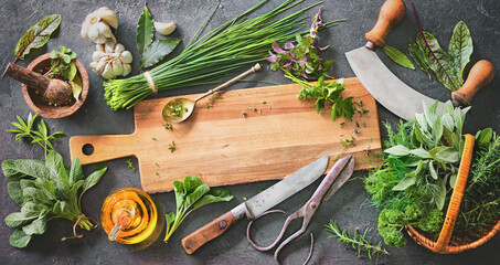 Various fresh herbs from garden with kitchen utensils on rustic table