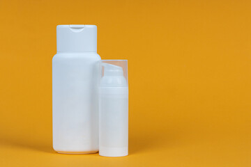 White containers of cosmetics on yellow background. Skincare product set. Face and body care concept.