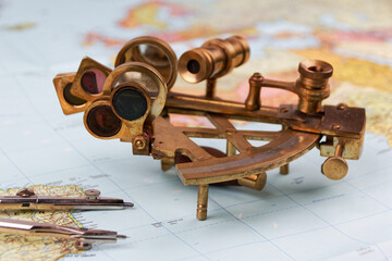 nautical sextant with optics lying on paper world map  © HighDispersion