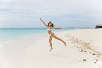 Fototapeta na wymiar Mädchen am Sandstrand freut sich über Urlaub im Paradies 