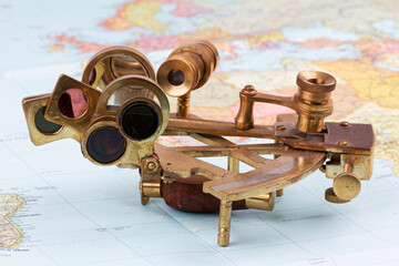 nautical sextant with optics lying on paper world map