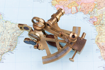 nautical sextant with optics lying on paper world map