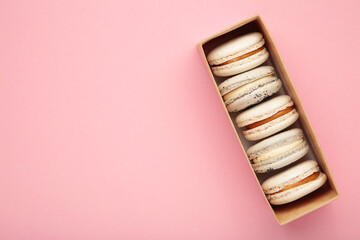 Pastel macaroons in box on pink background. Space for text