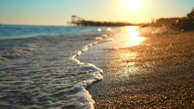 Blue sea wave, white foam, golden sand beach, turquoise ocean water and waves from seashore close up. Tourist travel on summer holidays on tropical island. Beauty nature landscape on sun rays sunset.