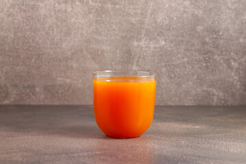 Fresh Carrot Juice in glass on brown background, side view, selective focus. Vegetable juice, natural antioxidant, detox. Raw food diet