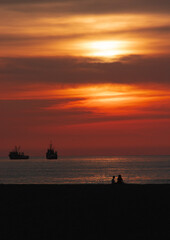Naklejka na ściany i meble Sunset at Chinchorro beach, with the red sun slowly going down