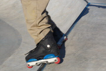 Aggressive inline skater grinds on rail coping in concrete pool. Roller blader doing grind trick in...