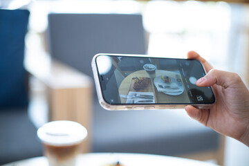 Woman taking a picture of food with a mobile phone in a cafe