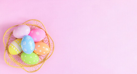 Fototapeta na wymiar Happy Easter holiday greeting card concept. Colorful Easter Eggs and spring flowers on pastel pink background. Flat lay, top view, copy space.