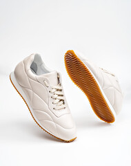 A mockup of urban style female white footwear. The shoes are positioned levitating with the white background, which makes a creative abstract display with the concept of modern fashion and comfort.