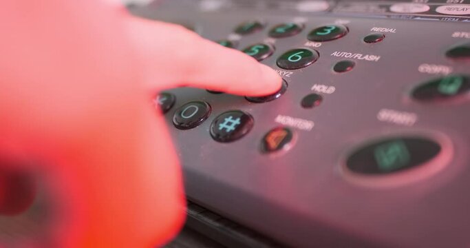 Man's hand dials 911 rescue service on an old push-button telephone. Side view, close-up