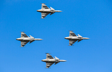 Formation of four military fighters flying in unison at the air show.