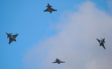 Formation of four military fighters flying in unison at the air show.