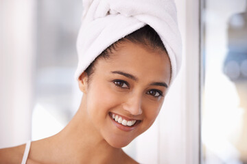 Treating herself to a hair mask. A young woman with a towel wrapped around her hair.