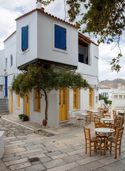 Fototapeta na wymiar Greece. Tinos island Cyclades. Outdoors traditional cafe with yellow windows at Pyrgos village