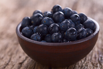 Fresh raw Patagonian Calafate berries (lat. Berberis heterophylla) in rustic bowl, photographed on...