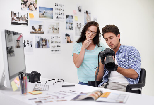 Looking for the best image. A photographer looking at his images in his office with his assistant.